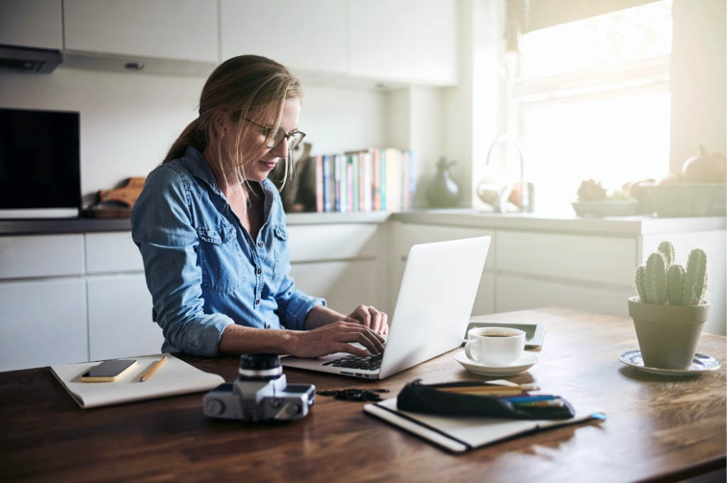 Woman working at home on laptop as photographer for extra income